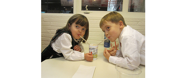 2 kids sharing a milkshake